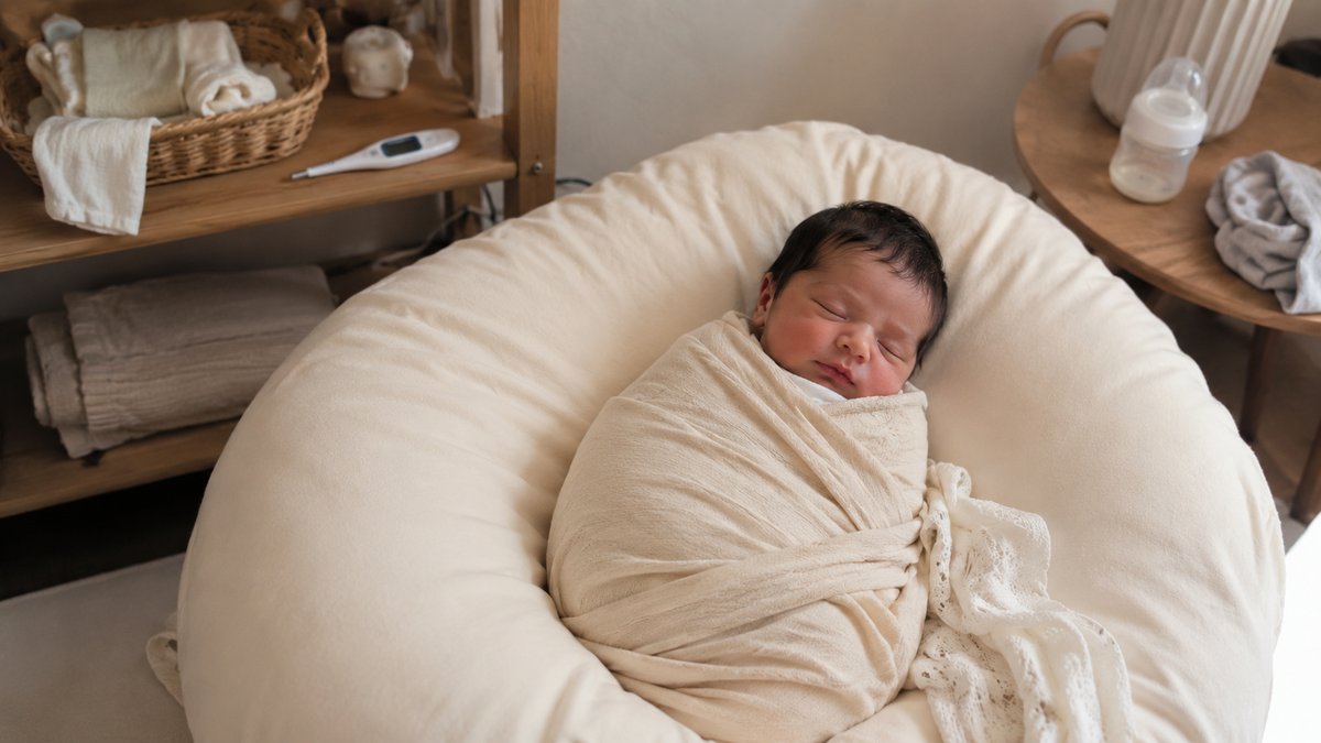 Recém-nascido adormecido enrolado numa manta suave durante sessão de fotografia newborn em Portugal